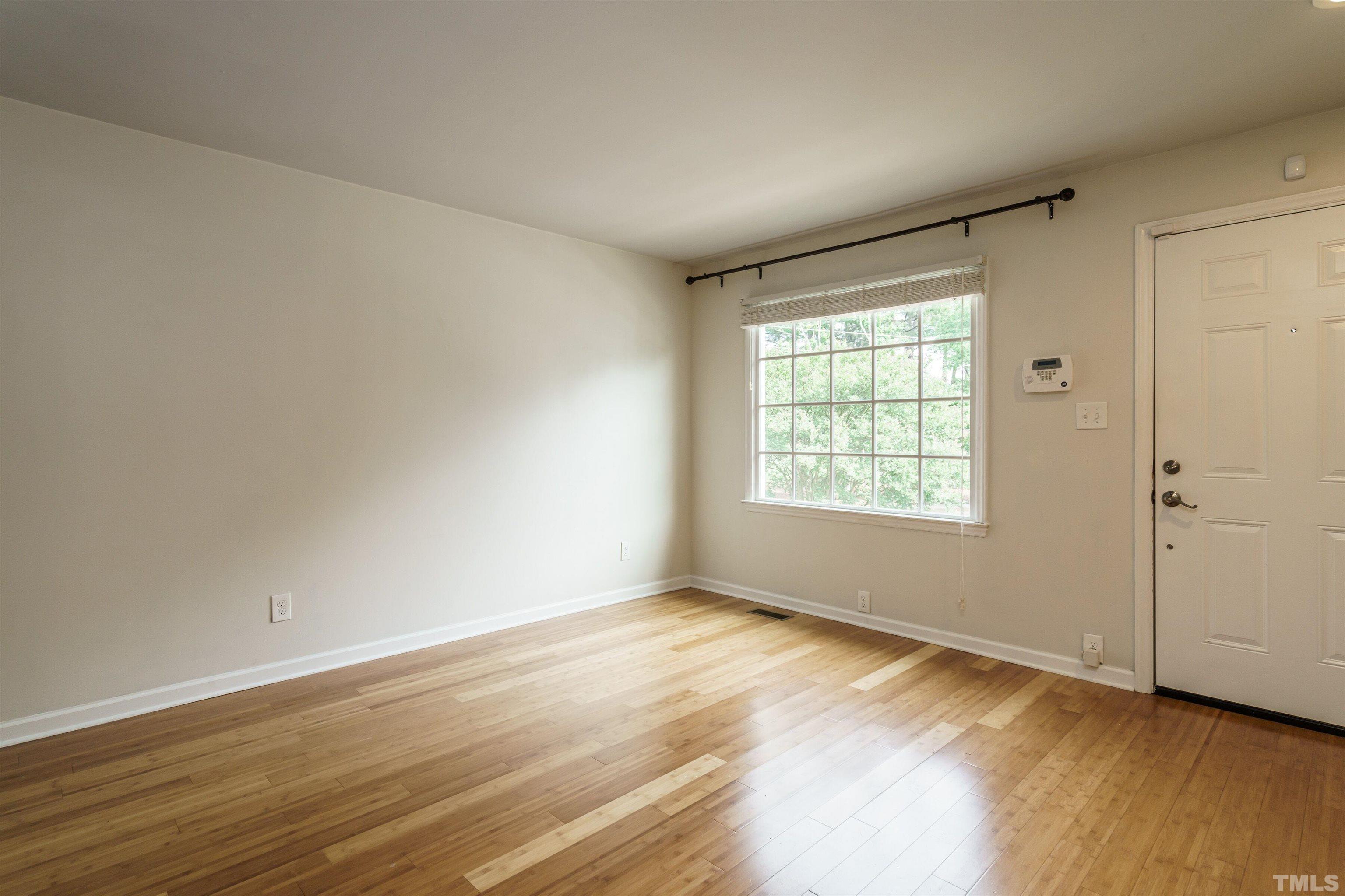 2502 Noble Road Raleigh, NC 27608 - Photo 4 of 19 a view of an empty room with wooden floor and a window