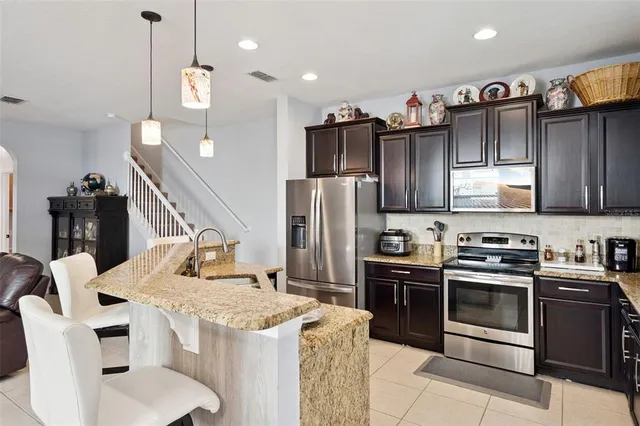 a kitchen with stainless steel appliances granite countertop a sink a stove and a refrigerator