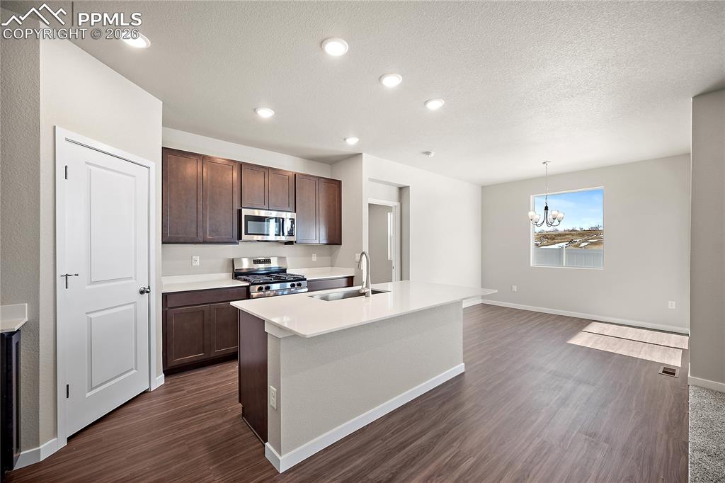 9653 Pinpoint Drive Fountain, CO 80817 - Photo 12 of 34 a kitchen with stainless steel appliances granite countertop a stove top oven a sink a refrigerator and white cabinets with wooden floor