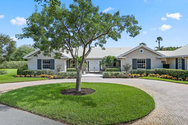 a front view of a house with a garden and trees