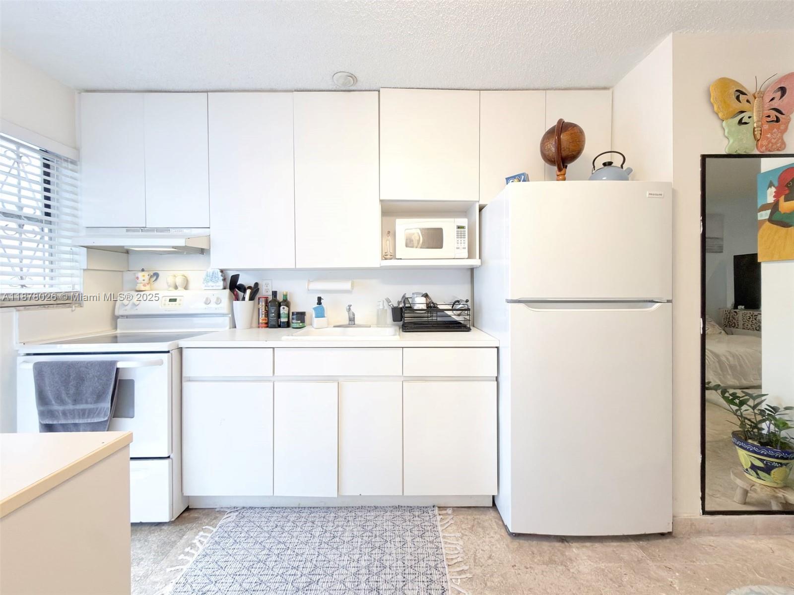 221 Meridian Avenue, Unit 211 Miami Beach, FL 33139 - Photo 3 of 20 a kitchen with a refrigerator a stove a microwave a sink and cabinets