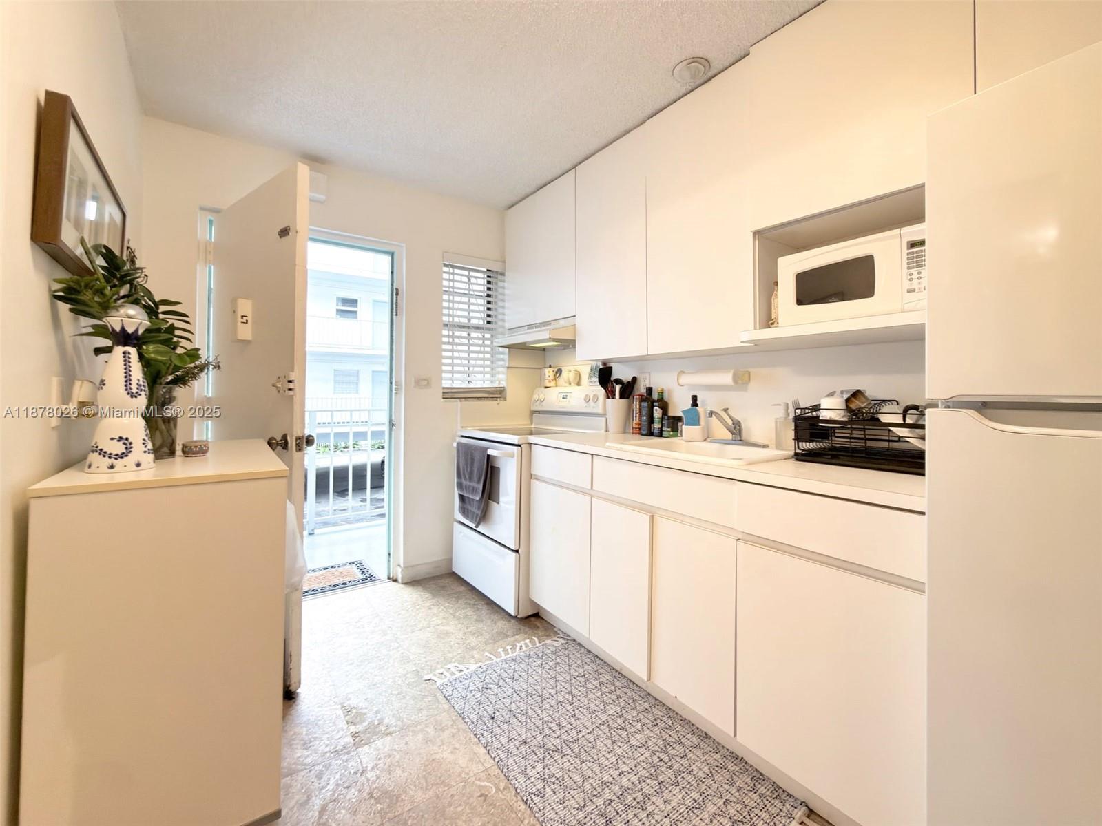 221 Meridian Avenue, Unit 211 Miami Beach, FL 33139 - Photo 4 of 20 a kitchen with a sink a stove and refrigerator