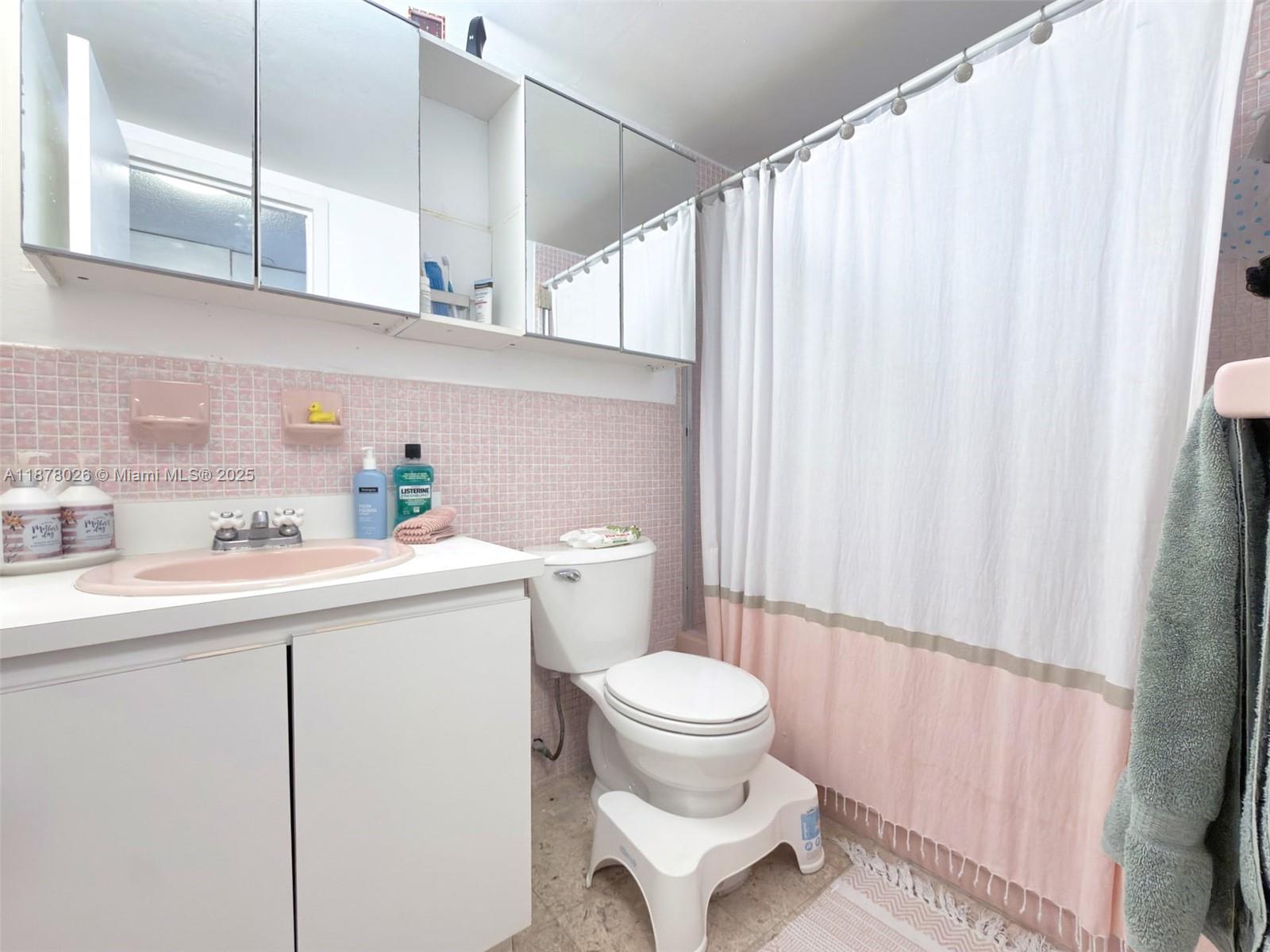 221 Meridian Avenue, Unit 211 Miami Beach, FL 33139 - Photo 6 of 20 a bathroom with a sink a toilet and shower curtain