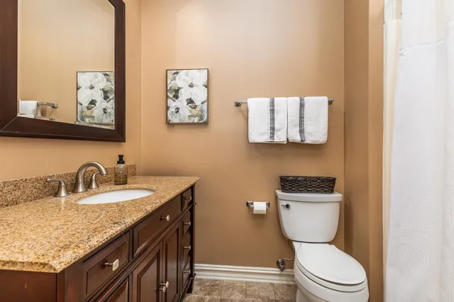 a bathroom with a granite countertop toilet sink and mirror