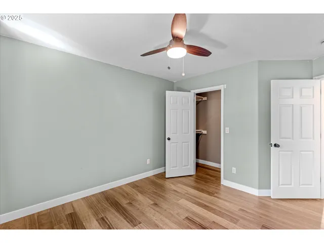a view interior of a house with wooden floor a ceiling fan and kitchen space