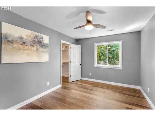 a view of an empty room with window and wooden floor
