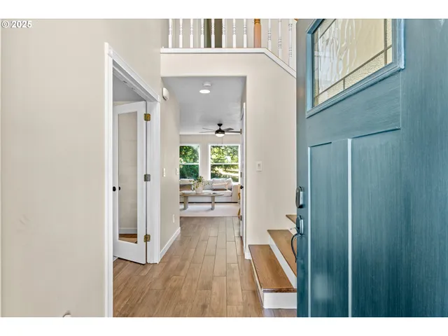 a view of a hallway with wooden floor a livingroom and front door