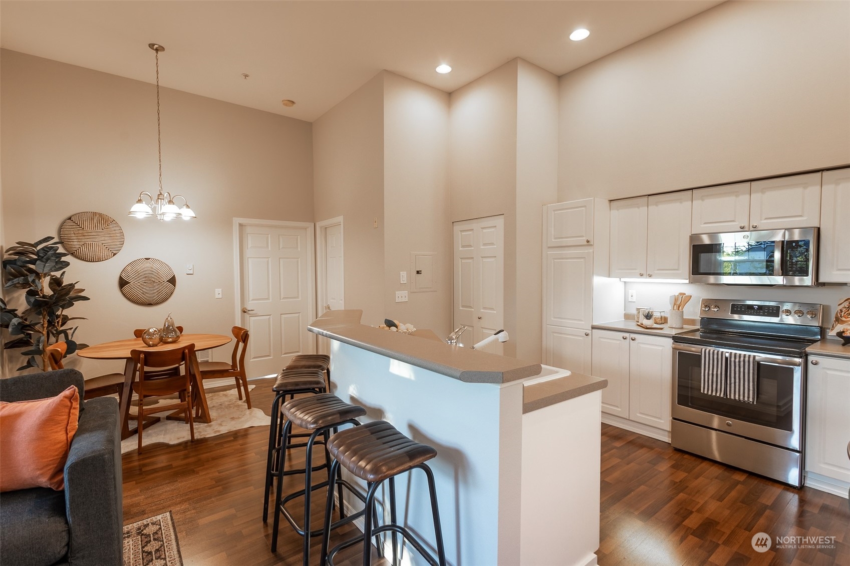 16125 Juanita Woodinville Way Northeast, Unit 2201 Bothell, WA 98011 - Photo 17 of 35 a large kitchen with kitchen island a stove a sink a dining table and chairs with wooden floor