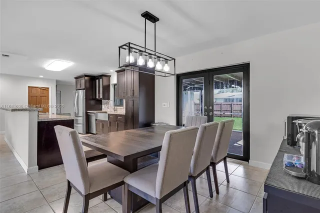 a kitchen with stainless steel appliances granite countertop a dining table chairs refrigerator and microwave