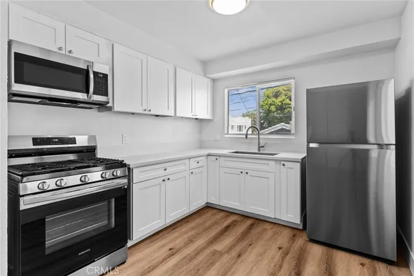 a kitchen with cabinets stainless steel appliances and wooden floor