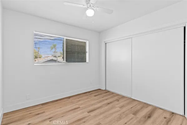 an empty room with wooden floor and fan