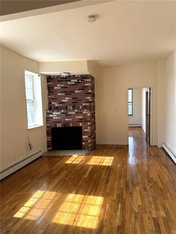 a view of empty room with wooden floor and fireplace