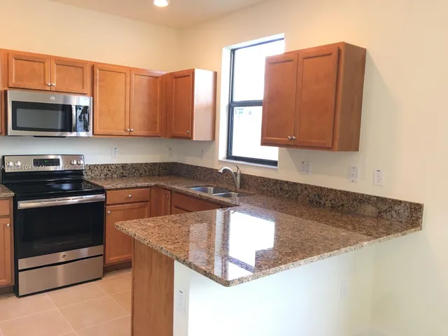 a kitchen with granite countertop a sink a stove and a microwave