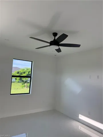 an empty room with a window and ceiling fan