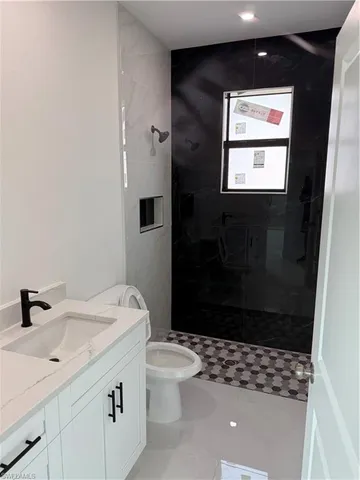 a bathroom with a sink a toilet a shower and a window