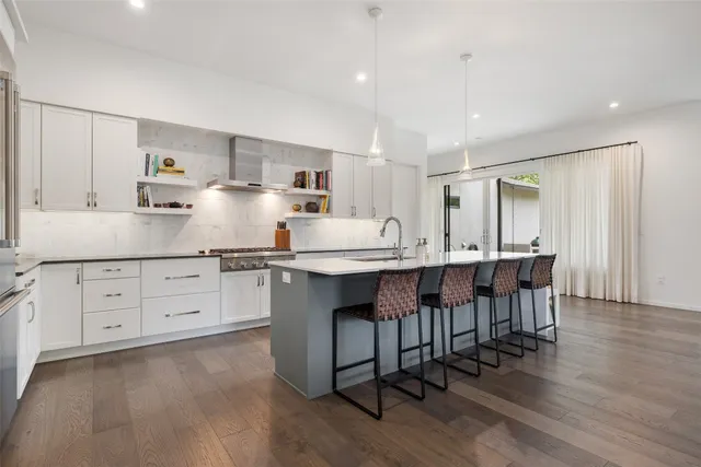 a kitchen with stainless steel appliances kitchen island granite countertop a table chairs sink and cabinets