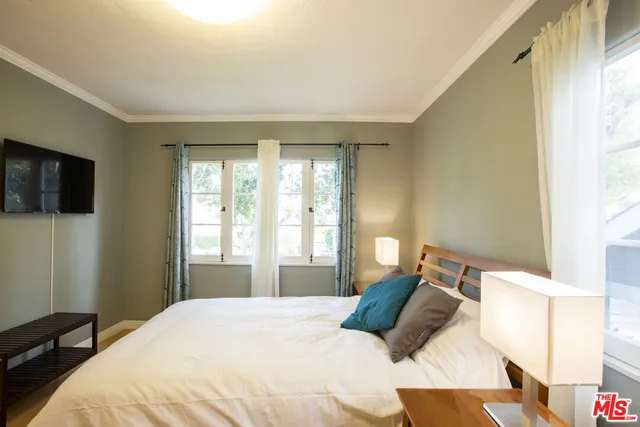 a bedroom with a bed tv and window