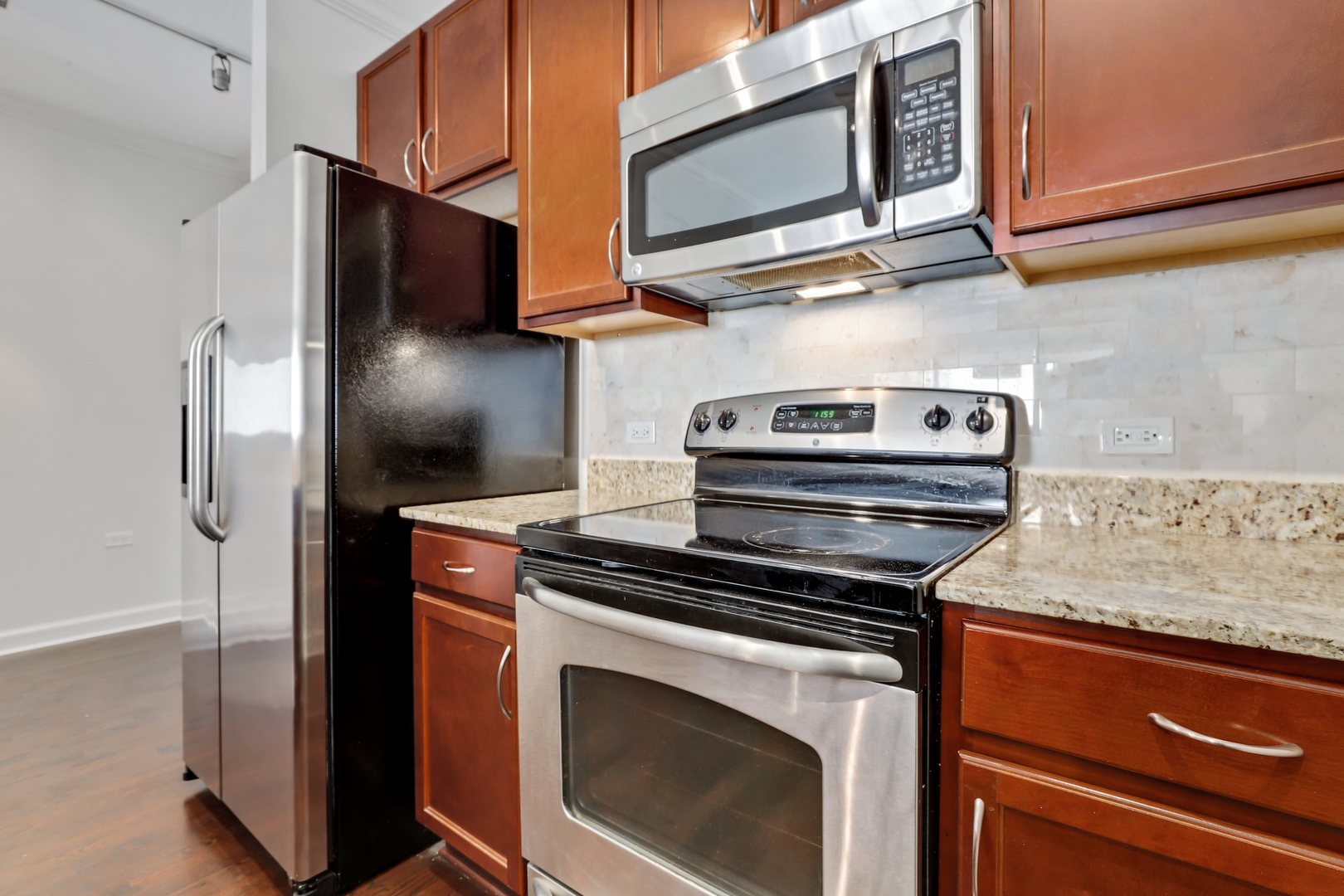 100 East 14th Street, Unit 1908 Chicago, IL 60605 - Photo 11 of 20 a kitchen with stainless steel appliances granite countertop white cabinets and a stove top oven