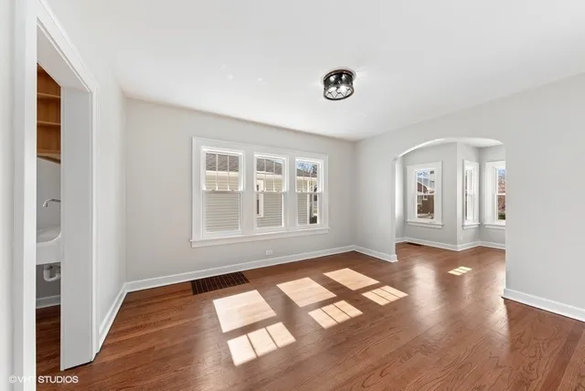 a view of an empty room with window and wooden floor
