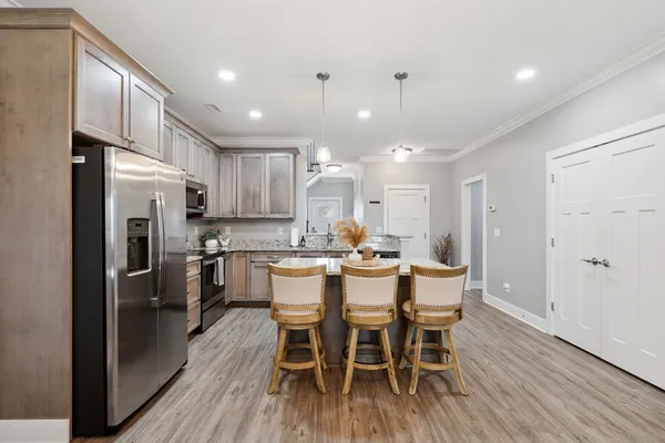 a kitchen with kitchen island granite countertop a center island stainless steel appliances cabinets and wooden floor