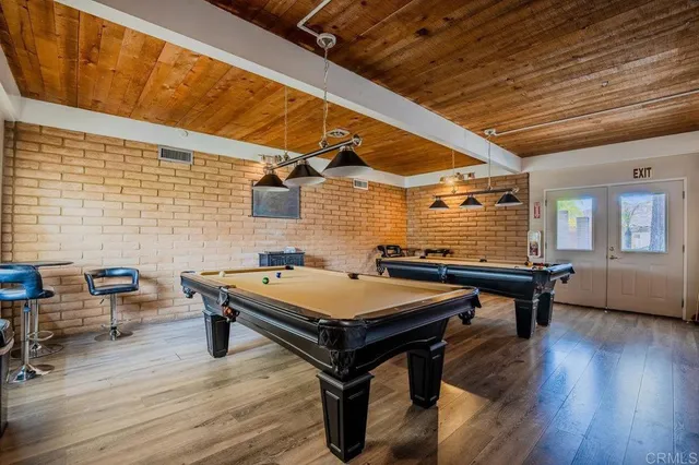 a room with furniture pool table wooden floor and windows