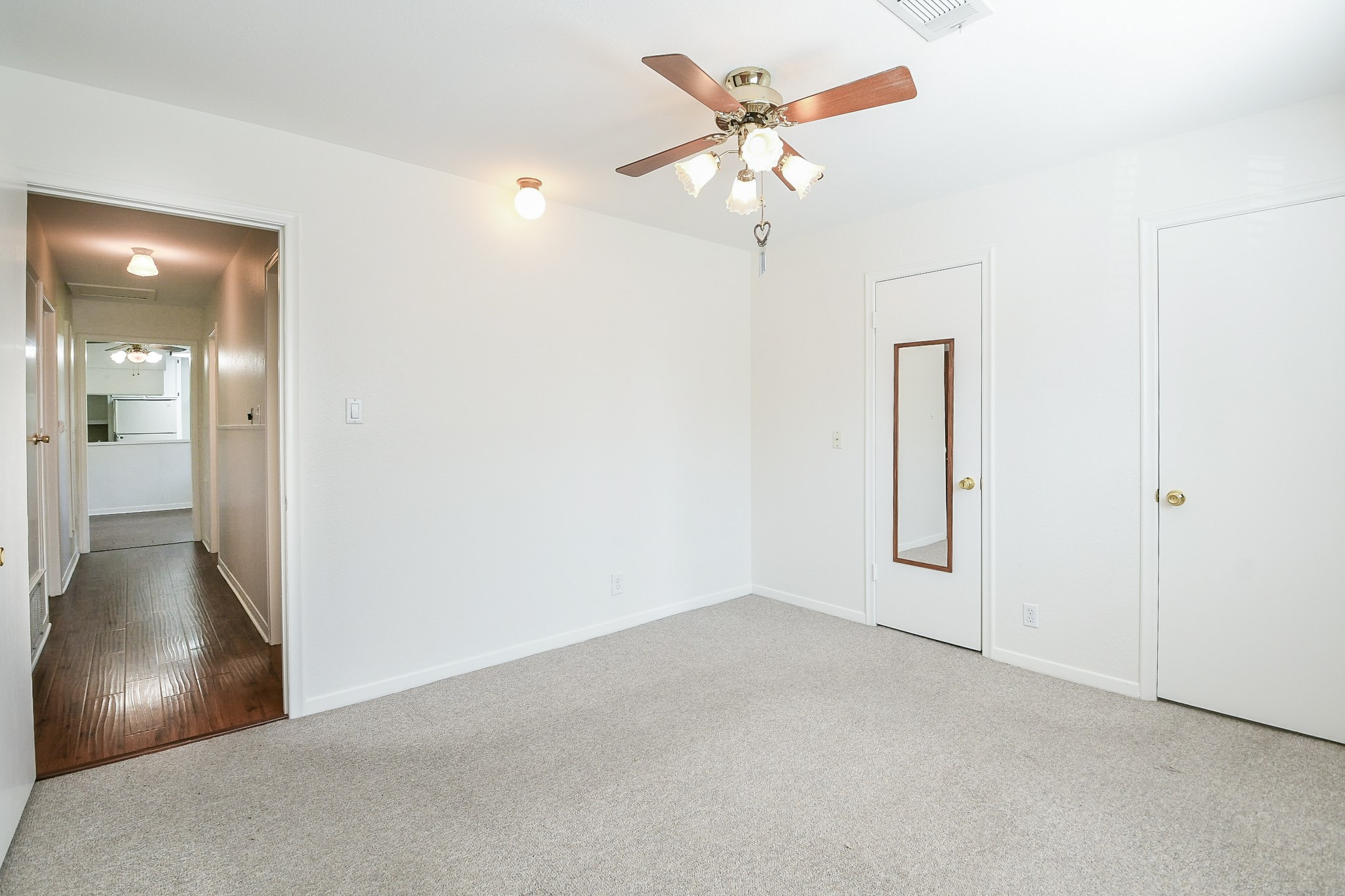129 Cannon Street Clute, TX 77531 - Photo 17 of 28 an empty room with a chandelier fan and wooden floor