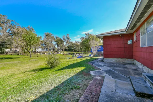 a view of a yard in front of a house with large windows