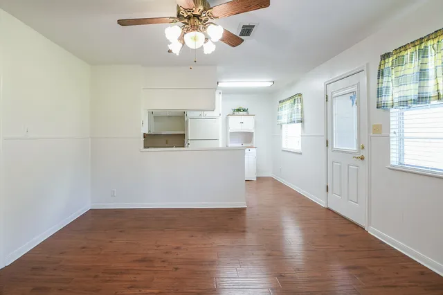 a view of an empty room with wooden floor and a window