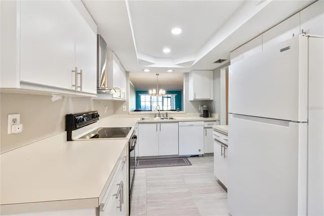 a kitchen with a refrigerator a stove top oven and white cabinets
