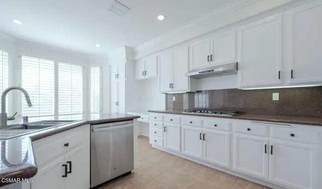 a kitchen with granite countertop white cabinets white stainless steel appliances and sink