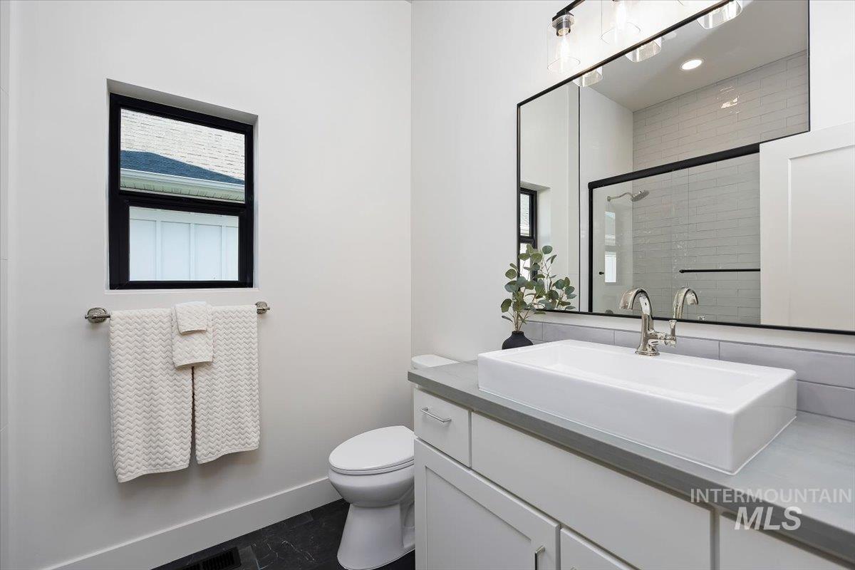 3068 Moonrise Road Twin Falls, ID 83301 - Photo 26 of 43 Wood-finish flooring, built-in cabinetry with dark hardware, solid surface countertop, white subway tile backsplash, and a wall-mounted hanging rod