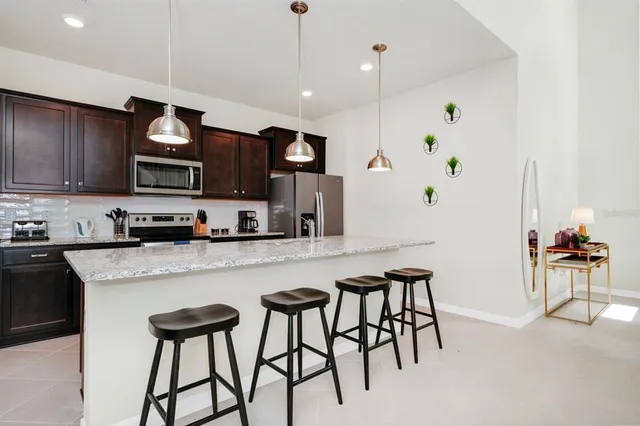 a kitchen with stainless steel appliances granite countertop a stove top oven a sink a dining table and chairs with wooden floor