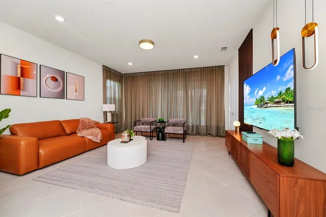 a living room with furniture a flat screen tv and a floor to ceiling window