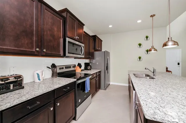 a kitchen with stainless steel appliances granite countertop a sink a stove and a refrigerator