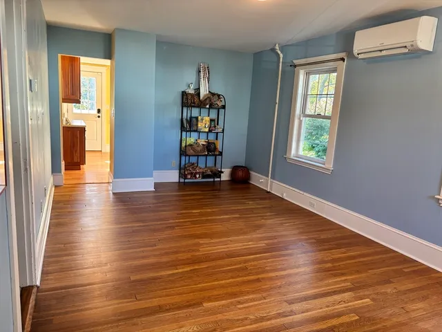 an empty room with wooden floor and windows with curtains