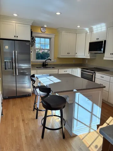 a kitchen with granite countertop a table chairs microwave and refrigerator