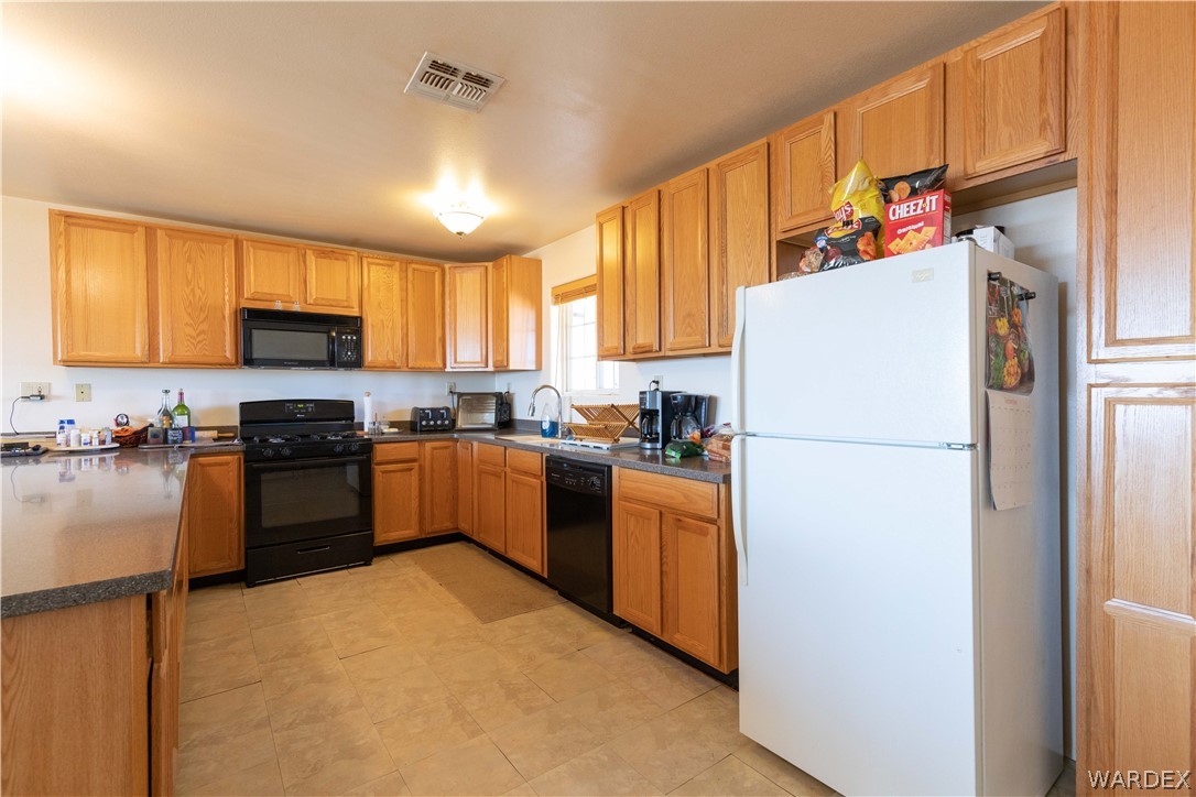 2136 Dewey Road Golden Valley, AZ 86413 - Photo 13 of 44 a kitchen with granite countertop a refrigerator a stove top oven a sink and dishwasher