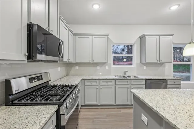 a kitchen with stainless steel appliances granite countertop a sink stove and microwave