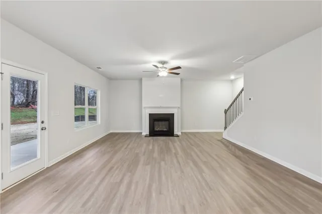 a view of an empty room with wooden floor fireplace and a window
