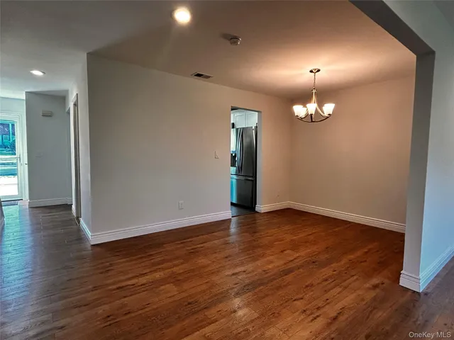 an empty room with wooden floor and chandelier