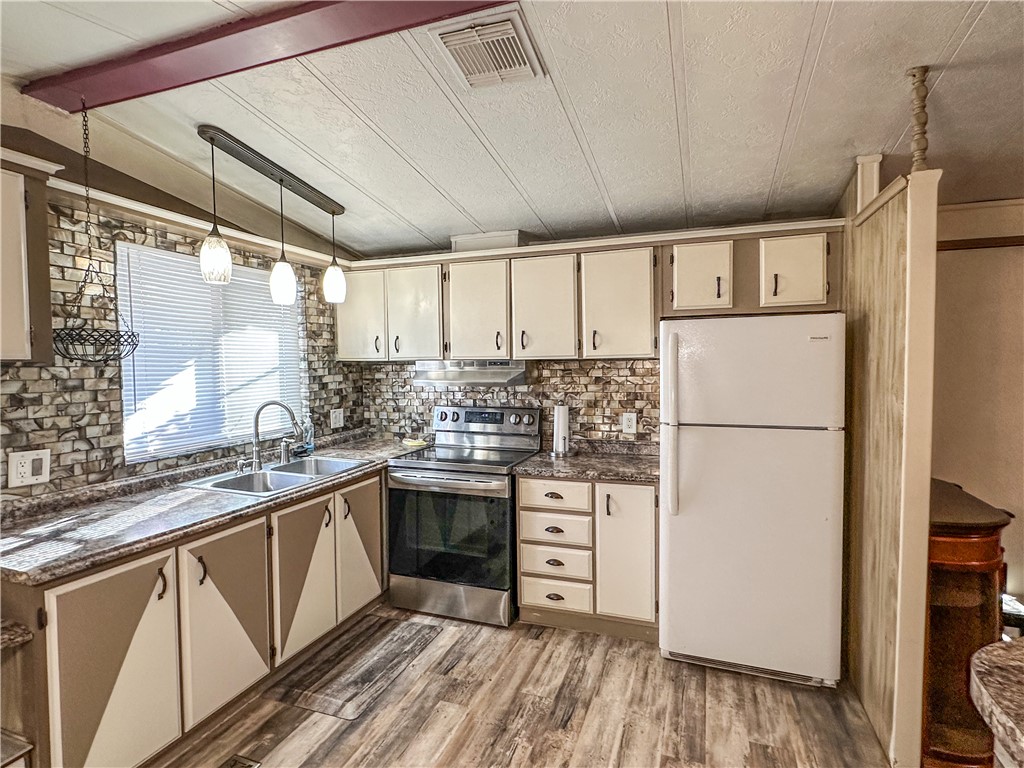 1655 Ramar Road Bullhead City, AZ 86442 - Photo 11 of 49 Kitchen with dark countertops, cream cabinets, freestanding refrigerator, stainless steel electric range oven, and light wood-style flooring
