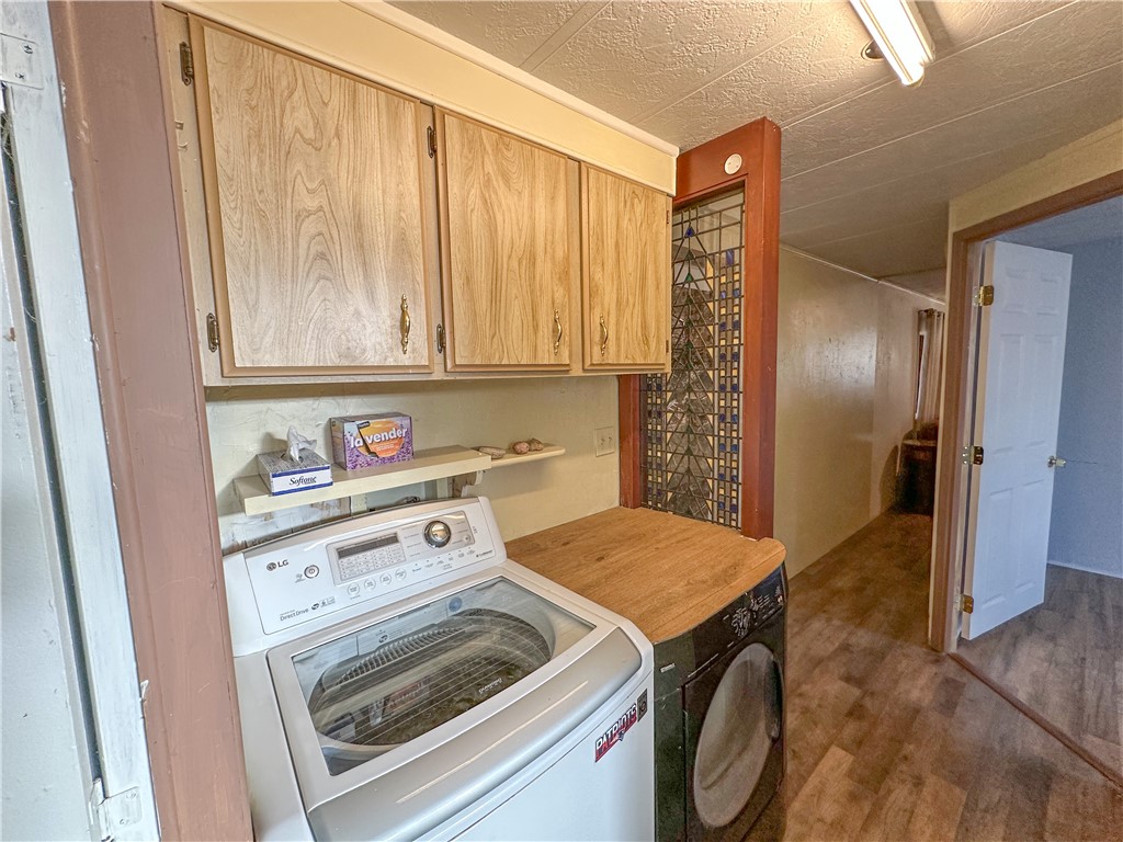 1655 Ramar Road Bullhead City, AZ 86442 - Photo 16 of 49 Laundry area featuring dark wood-type flooring, washer and clothes dryer, cabinet space, and a textured ceiling