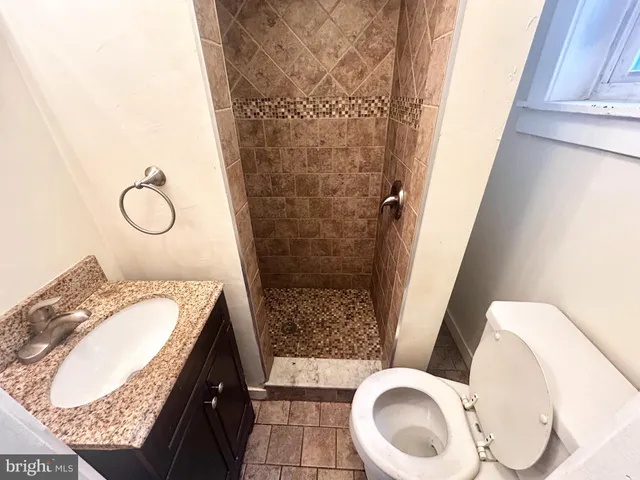 a bathroom with a granite countertop sink toilet and shower