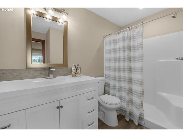 a bathroom with a sink a toilet a mirror and shower curtain
