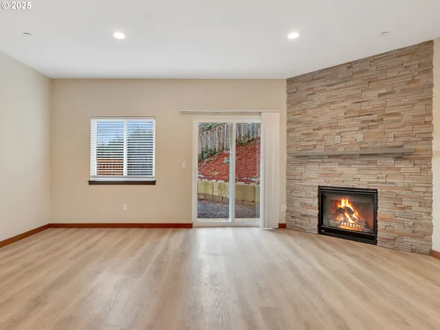 an empty room with wooden floor fireplace and windows