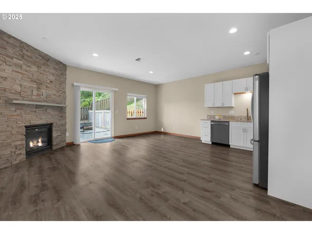 a view of empty room with kitchen and fireplace