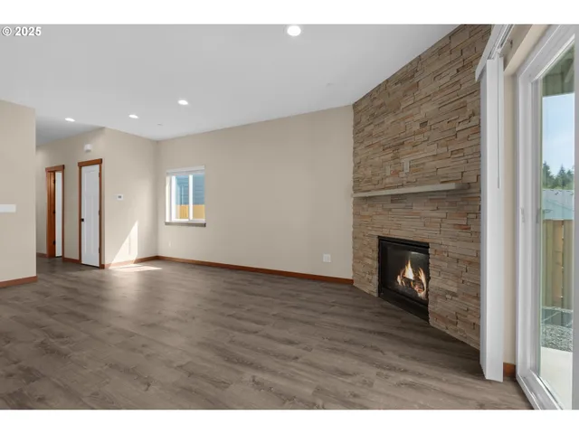 a view of an empty room with wooden floor fireplace and a window