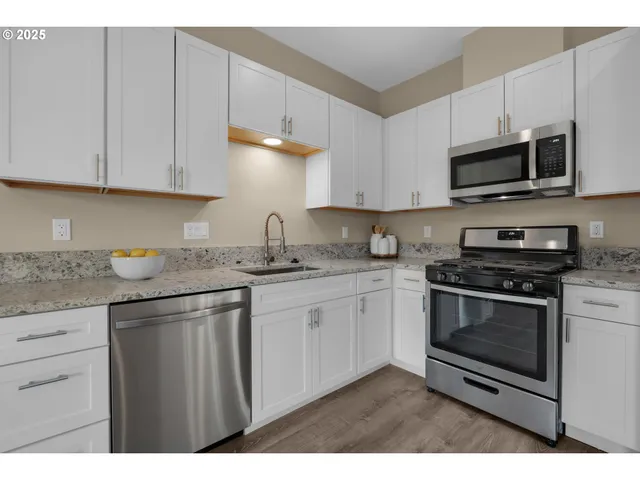 a kitchen with stainless steel appliances granite countertop a sink a stove a microwave and cabinets