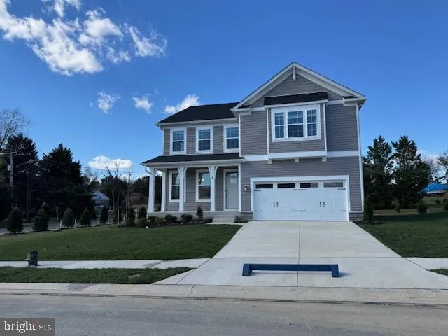 a white house with a small yard plants and large trees