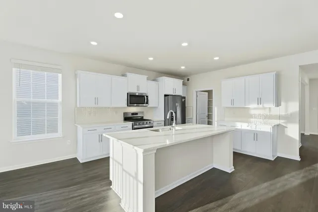 a kitchen with stainless steel appliances a sink a stove a refrigerator cabinets and a window